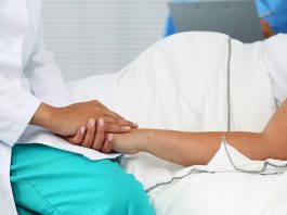 Friendly female medicine doctor hands holding pregnant woman's hand lying in bed for encouragement, empathy, cheering and support while medical examination. New life of abortion concept