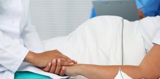 Friendly female medicine doctor hands holding pregnant woman's hand lying in bed for encouragement, empathy, cheering and support while medical examination. New life of abortion concept