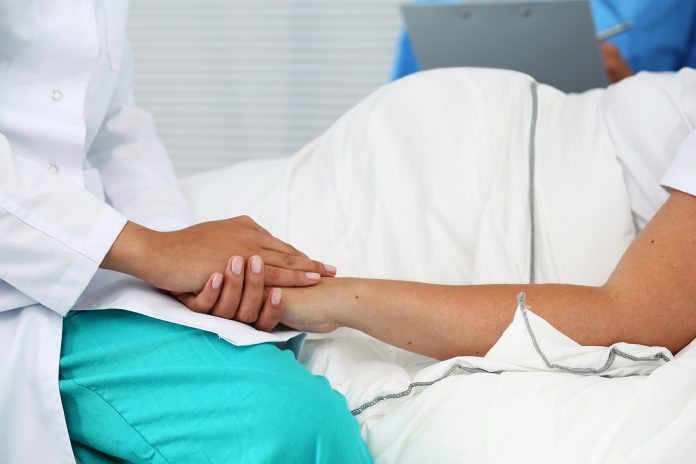 Friendly female medicine doctor hands holding pregnant woman's hand lying in bed for encouragement, empathy, cheering and support while medical examination. New life of abortion concept