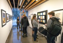 Visitors look at art on display in Kellogg Community College’s art gallery during the opening reception for the KCC Faculty Biennial Art Exhibition Jan. 24.