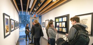 Visitors look at art on display in Kellogg Community College’s art gallery during the opening reception for the KCC Faculty Biennial Art Exhibition Jan. 24.