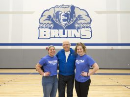 Volleyball players Madison Jones and Kameron Haley stand with Mick Haley in the Miller gym.