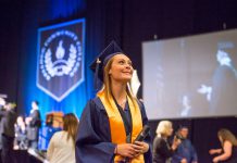 At graduation, a girl in cap and gown holds her diploma