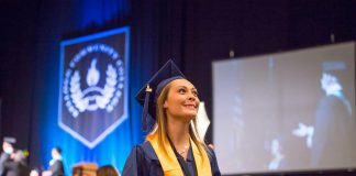 At graduation, a girl in cap and gown holds her diploma