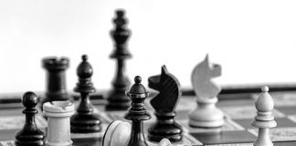 A black and white image of a chess board in play.