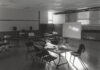 A black and white photo showing light falling through a window on a table in a classroom.