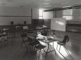 A black and white photo showing light falling through a window on a table in a classroom.