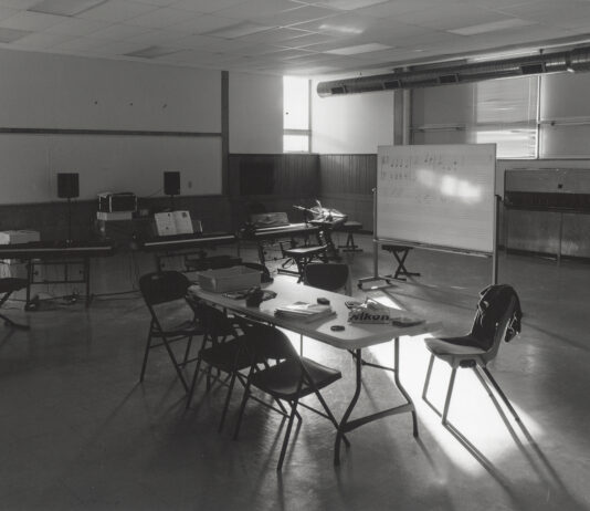 A black and white photo showing light falling through a window on a table in a classroom.