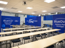 A training classroom featuring tables and chairs and blue walls with white Ford and BlueOval logos on them.