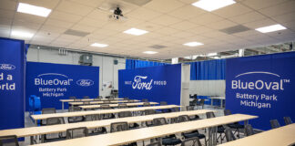 A training classroom featuring tables and chairs and blue walls with white Ford and BlueOval logos on them.