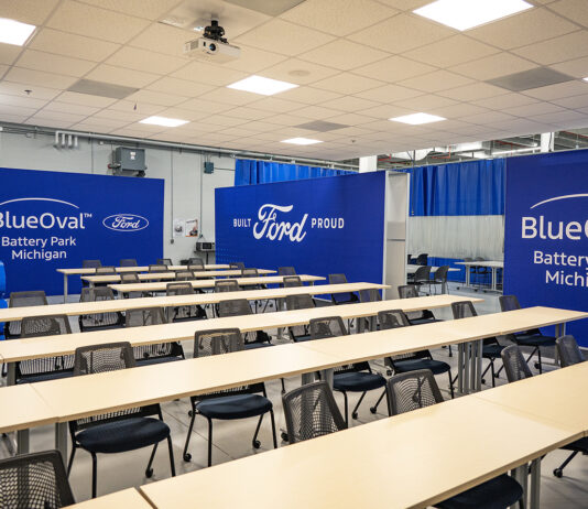 A training classroom featuring tables and chairs and blue walls with white Ford and BlueOval logos on them.