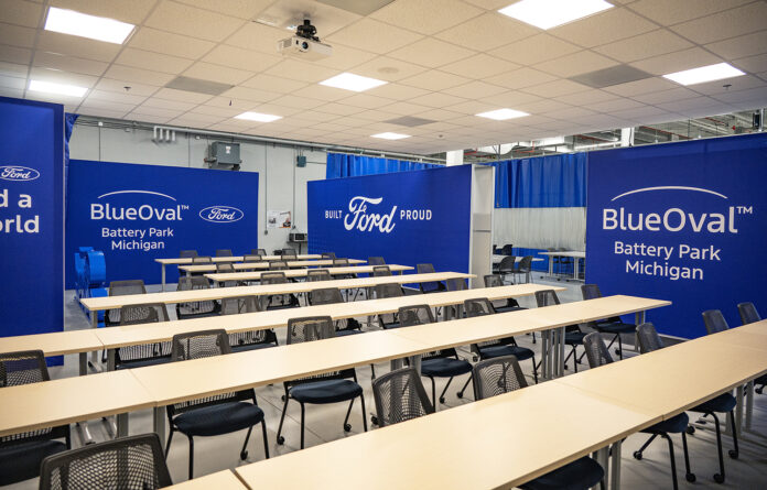 Ford BlueOval at the RMTC A training classroom featuring tables and chairs and blue walls with white Ford and BlueOval logos on them.