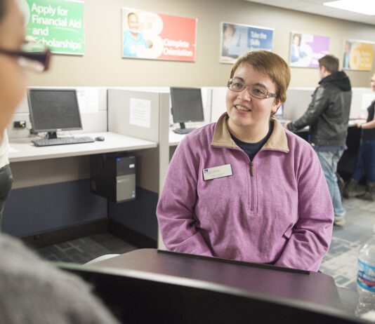 A student worker assists a visitor to the Hub.